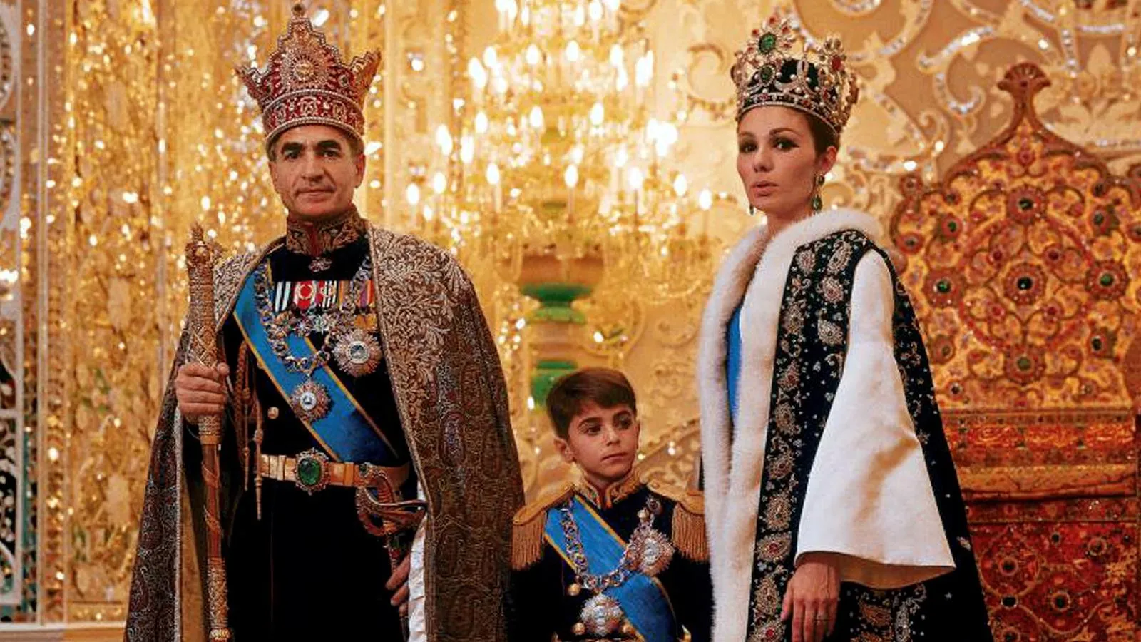 Мохаммед Реза Пехлеви со своей третьей женой и их сыном Резой в церемониальных одеждах перед троном. Global Look Press